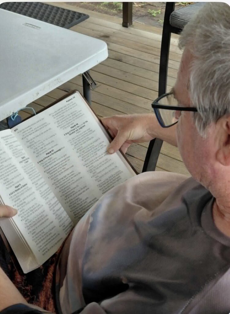 Looking over the shoulder of Glenn Schofield reading his Giant letter Bible.